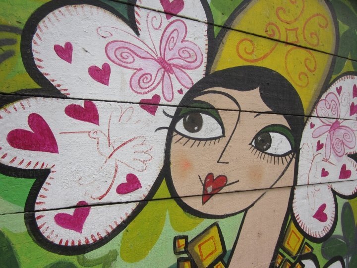 Street art mural of woman's face, hearts, butterflies.