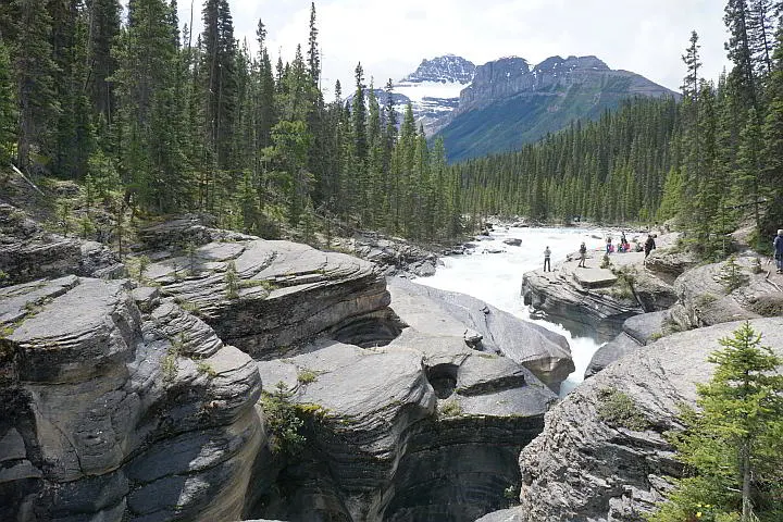 Mistaya Canyon Alberta with Rocky Mountains and tourists enjoying the falls.