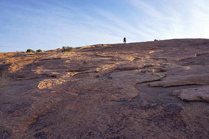 A hiker on the rock slab portion of Delicate Arch trail