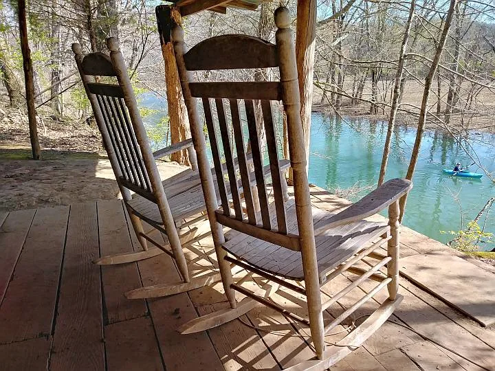 Two rocking chairs look out to kayaker in Chickamauga Creek