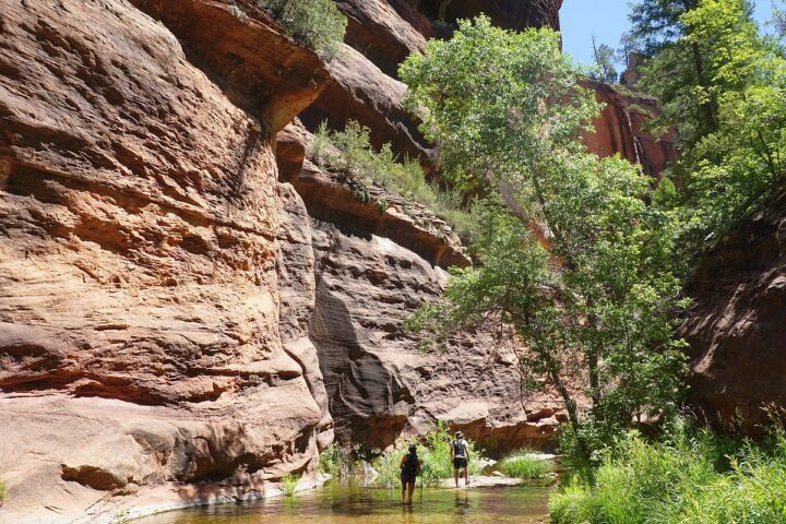 Two hikers in the creek along the Oak Creek Canyon hiking trail in Sedona, Arizona.
