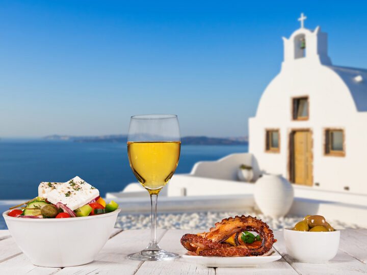 Glass of white wine, olives, octopus, and Greek salad are all traditional food of Greece.