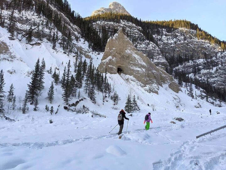 Two hikers dressed in winter hiking gear on a snowy trail.