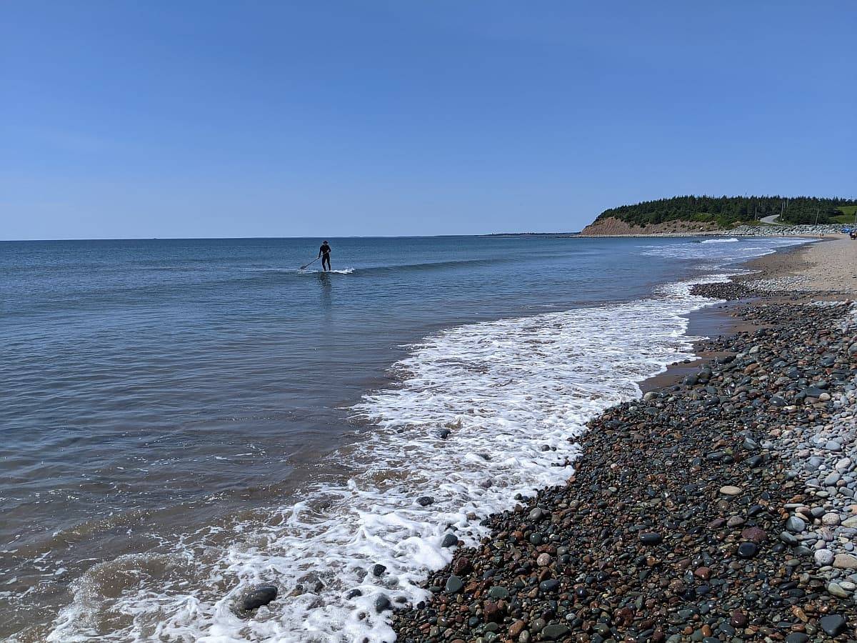 Paddleboarder riding a wave a Lawrencetown Beach.