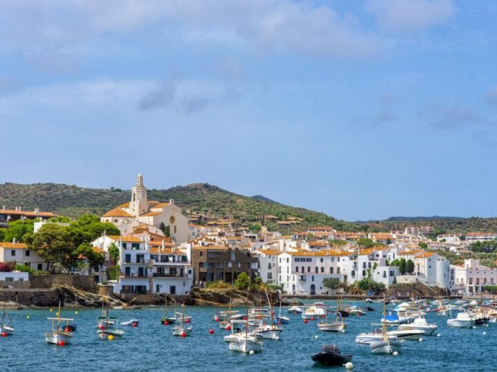 Boats in Cadaques harbor and white buildings on the coastline.