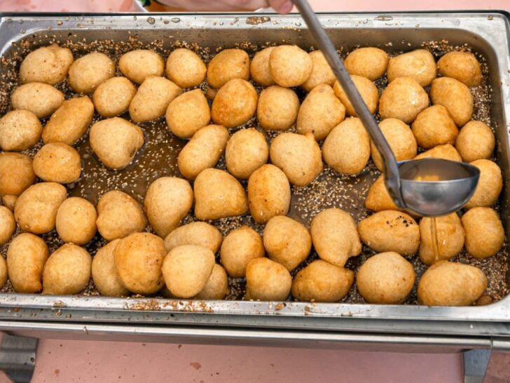 Greek dessert loukoumades with ladle pouring honey on top.