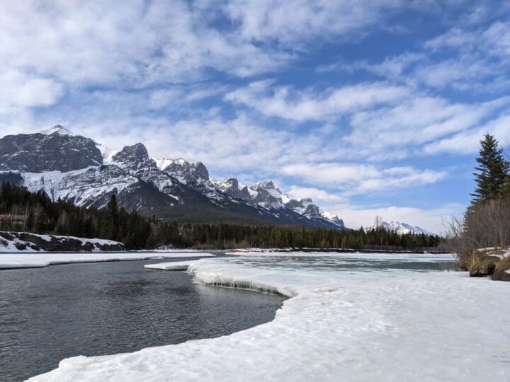 Snow capped Rocky Mountains, Bow River, and snow covered terrain in Canmore Alberta in winter.