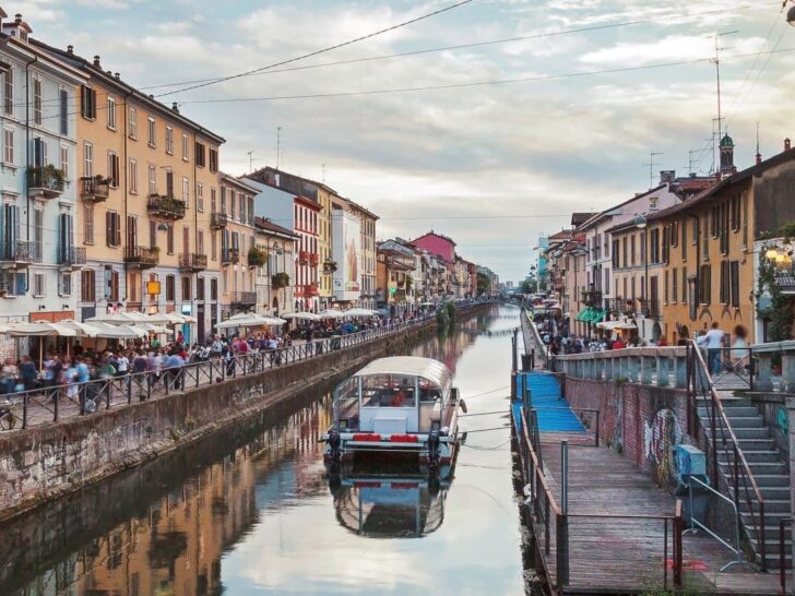 Boat in the canal alongside cafes and shops in Navigli district Milan.