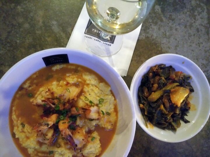 Shrimp n grits with collard greens side and glass of white wine at Tsunami Lafayette LA.