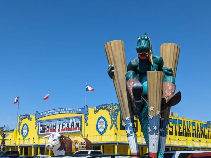 Big Texan Steak Ranch exterior, with sculpture of large green, cowboy boot wearing dinosaur.