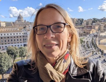 A smiling lone traveler at Castel Sant' Angelo rooftop with St Peter's Basilica in the background.